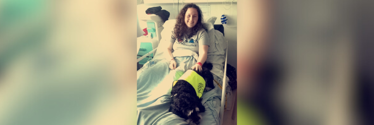 Woman smiling in hospital bed with her dog
