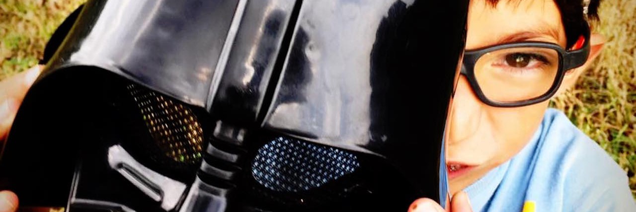 Explaining My Son's Facial Differences to Him boy holding a darth vadar mask