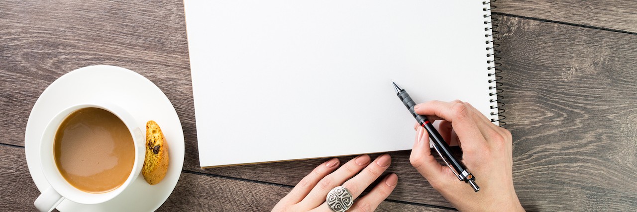 A Letter to My 15-Year-Old Self in the Psych Ward Woman writing letter with a cup of coffee next to her hands.