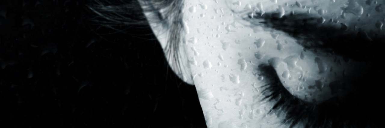 Close up image of half of a woman's face as she is dripping with water