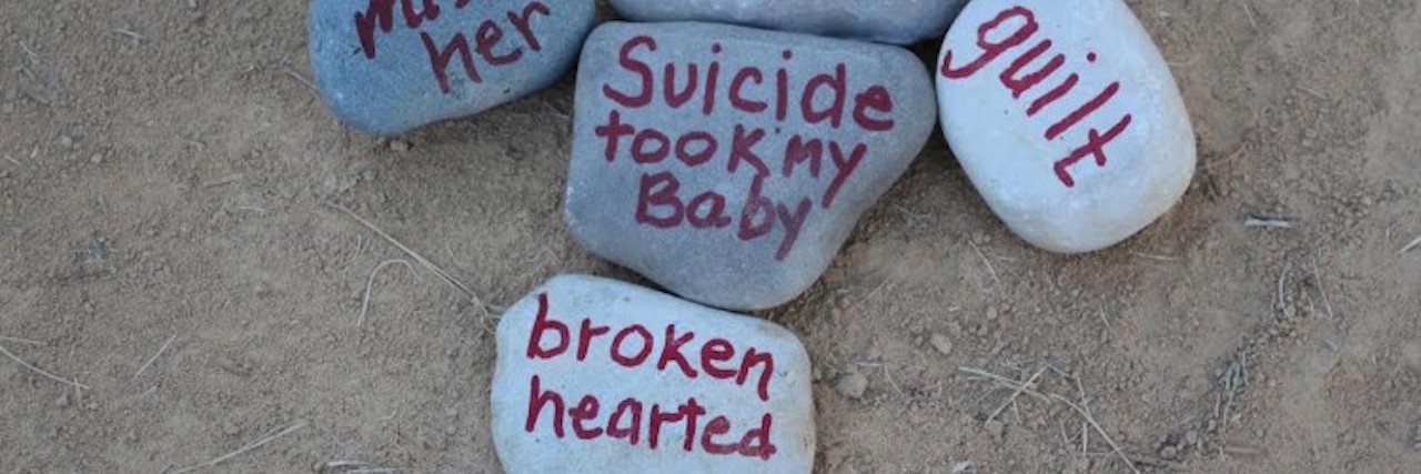 Rocks with words written on them in red marker: miss her, depression, guilt, suicide took my baby and broken hearted