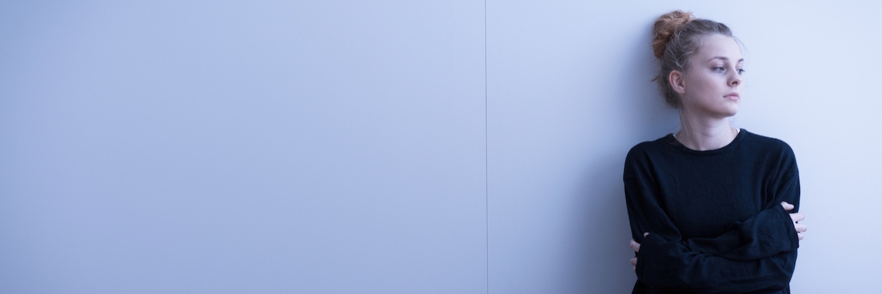 How Grieving Death by Suicide is Different than Grieving Other Deaths girl sits alone against a white wall