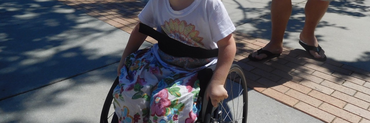 Heidi, a little girl with spinal muscular atrophy pushing her wheelchair.