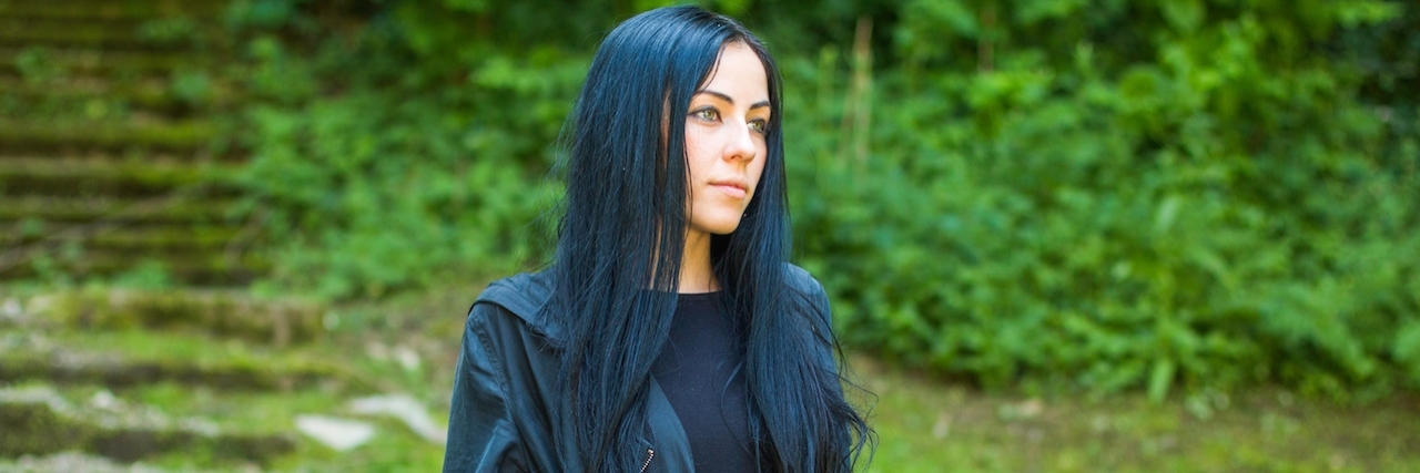 How Being Alone With My Thoughts Helped Me Cope With Depression Woman sitting in black coat on staris in a grassy landscape