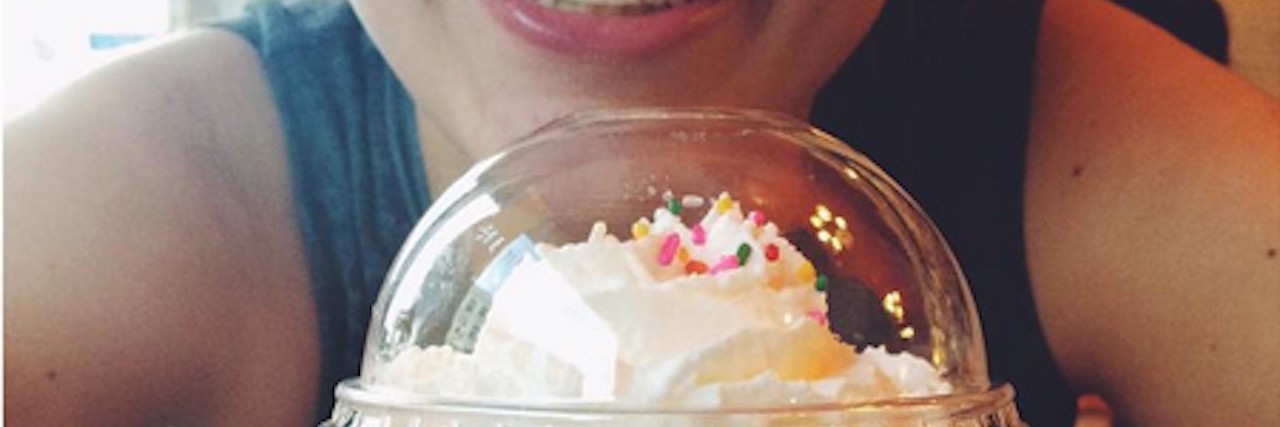 Woman smiling behind a cup of icecream.