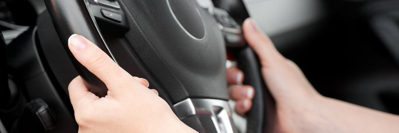 woman hands holding steering wheel in car