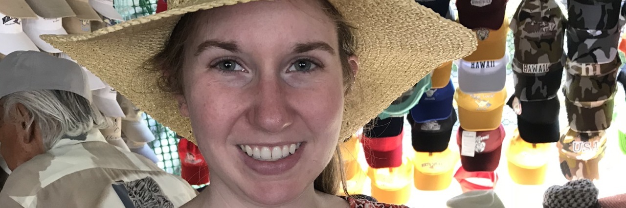 A photo of the writer in a sundress and hat, smiling.