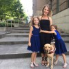 woman and two girls stand on steps with guide dog