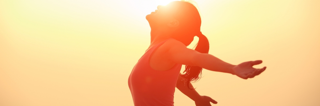 Finding the Positive Side To Depression Woman with arms wide open, basking in the sunrise