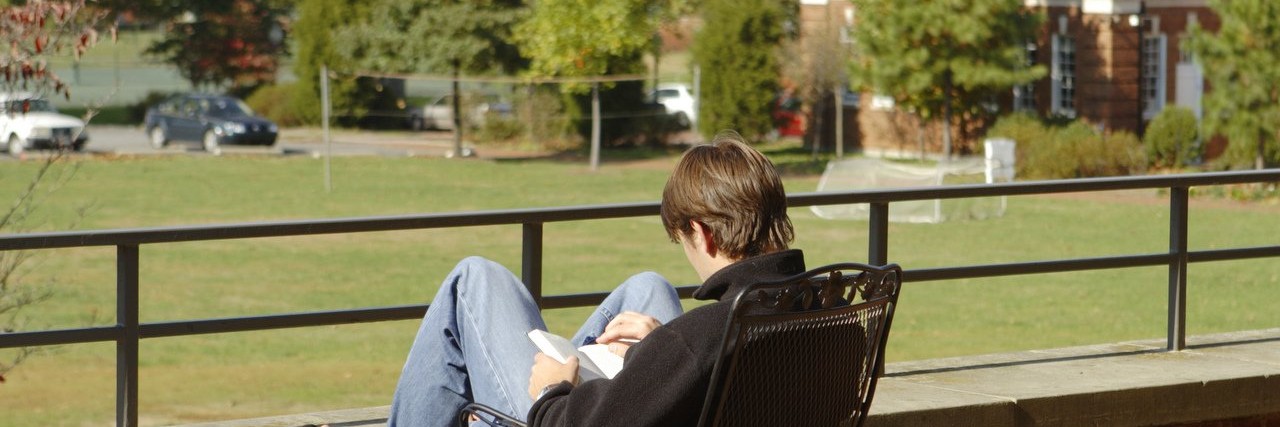 Young man reading on a deck at a college