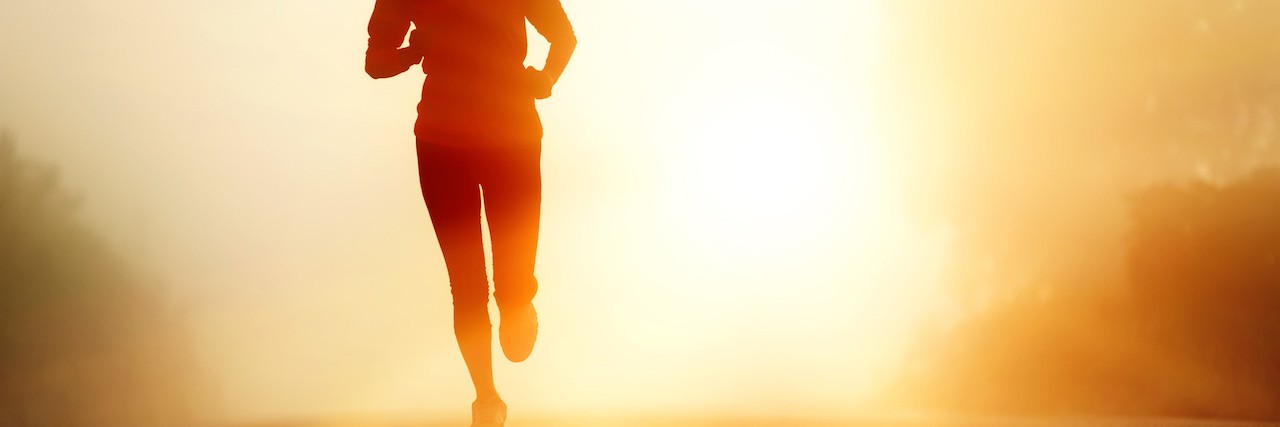 Woman running with sunrise behind her