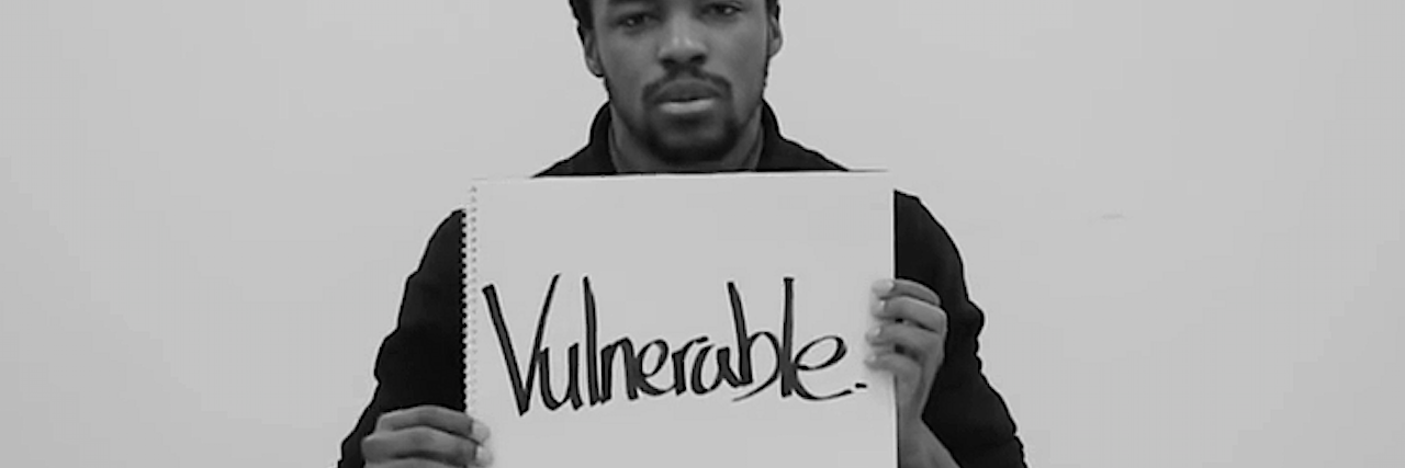 A man holding up a sign that says vulnerable