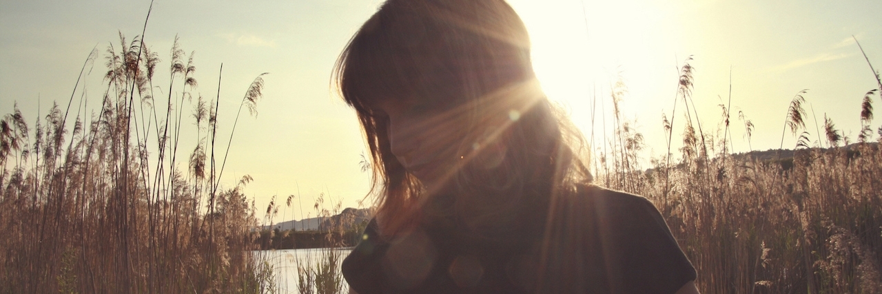 The One Person Who Makes You Smile in Depression A girl standing in front of the sun in a field
