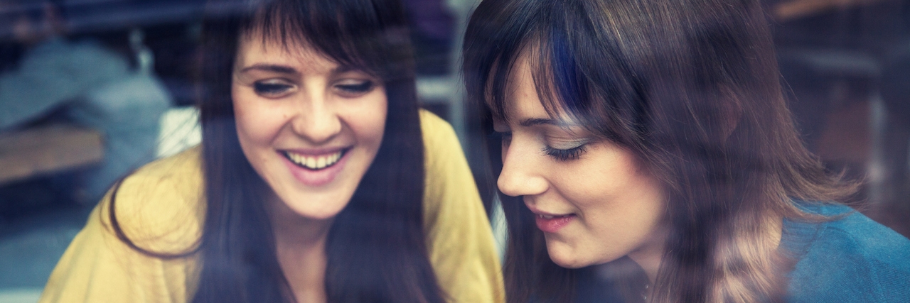 To the People Who Still Need Me in the Midst of My Mental Illnesses Two girls smiling as they use a smartphone in a cafe