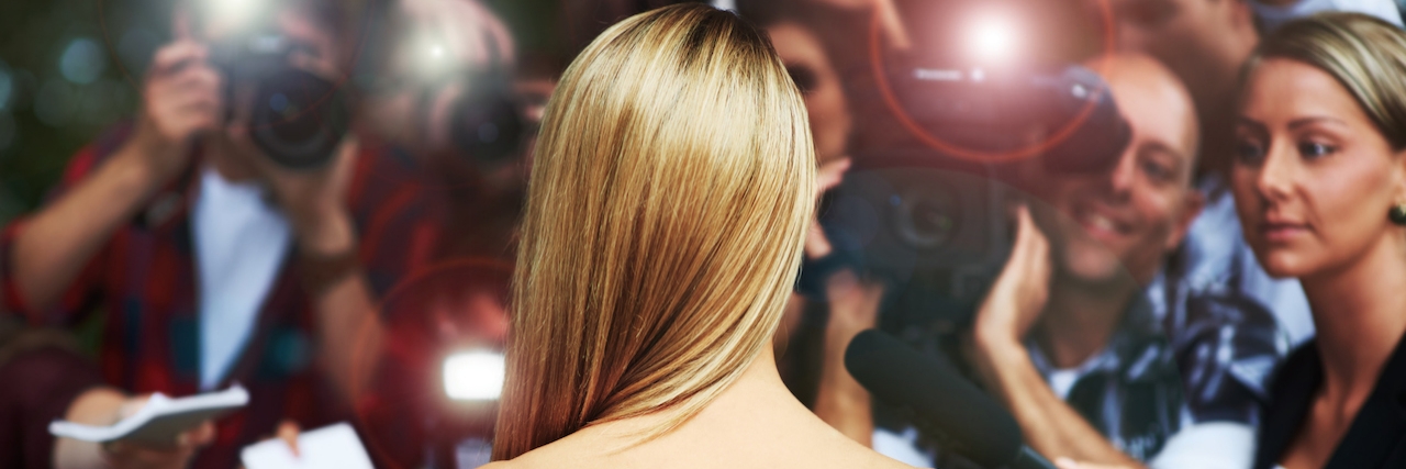 Concerns With the Increased Exposure of Bipolar Disorder a woman in a strapless dress surrounded by flashing cameras