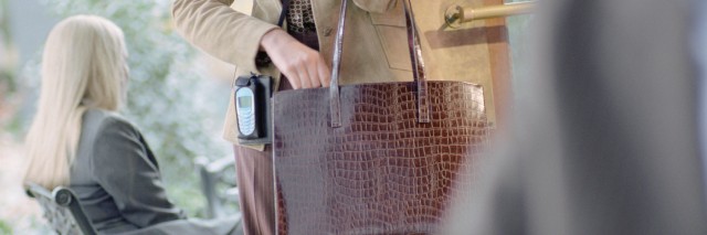 Businesswoman with to go coffee looking in purse at cafe.
