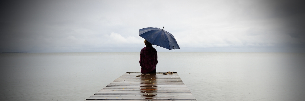 High-Functioning Depression: Answering 'How Are You?' A man holdning an umbrella, sitting at the end of a dock