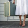 Woman leaving entrance door carrying two suitcases
