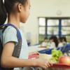 Girl holding food tray in school cafeteria.