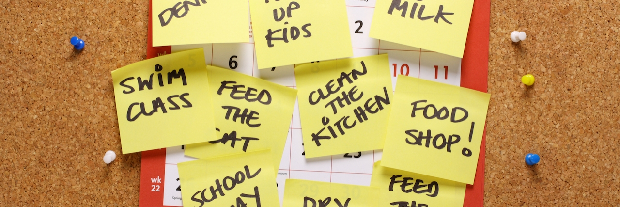 What People With High Functioning Depression Want Others to Understand A calendar on a cork notice board covered in yellow paper sticky notes with various household chores and errands