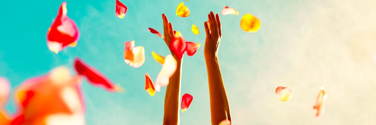 What I Realized After Recovering From Depression A woman with her hands in the air, throwing flowers