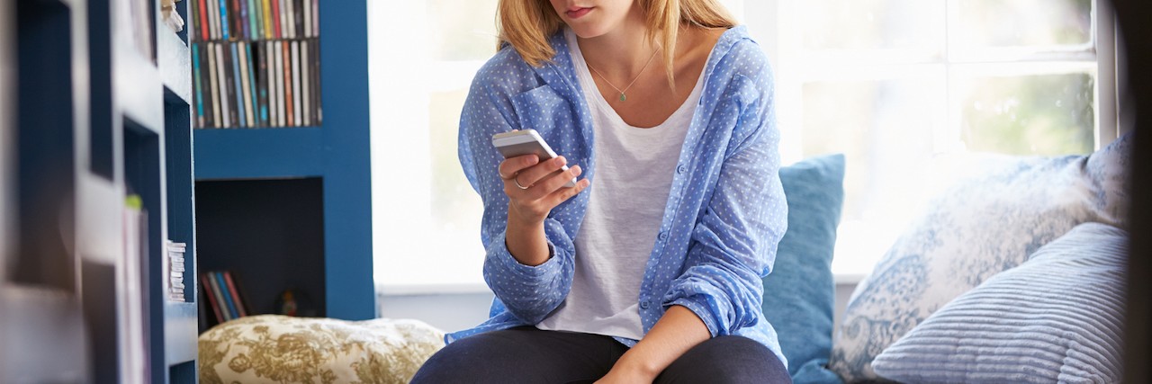 Woman Sitting On Couch At Home Using Mobile Phone