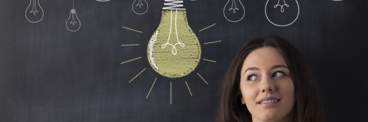 Starting a Rare Disease Nonprofit: What to Know Young business woman standing with her back against a blackboard. She is looking to a big glowing light bulb.