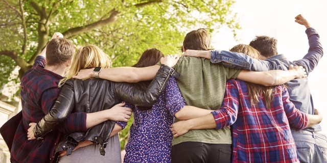 six friends with their arms around each other, back view