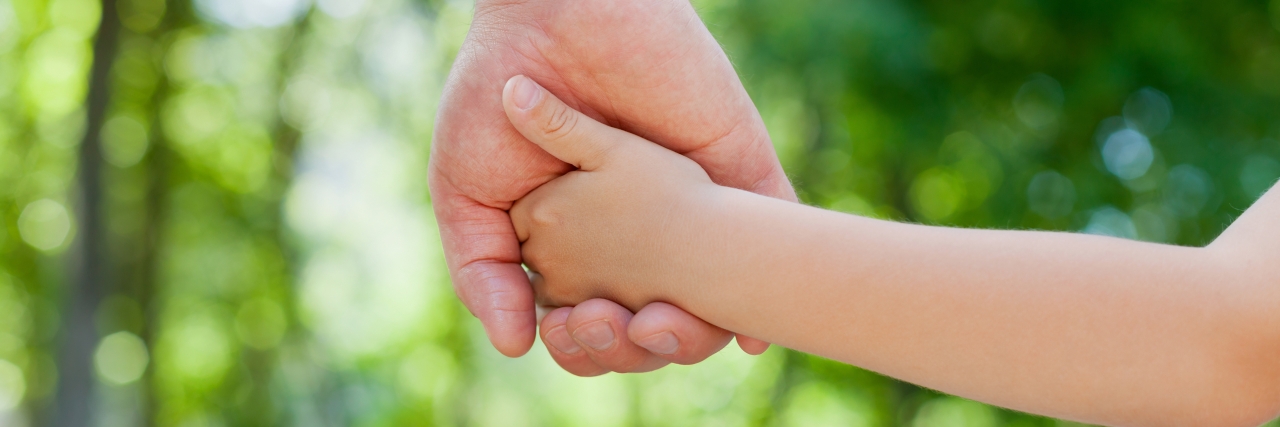 Reflecting on a Child's Down Syndrome Diagnosis Parent holds the hand of a little child.