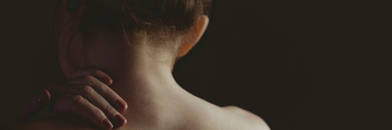 What You're Thinking During a Fibromyalgia Flare woman rubbing shoulder facing away