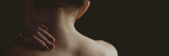 woman rubbing shoulder facing away