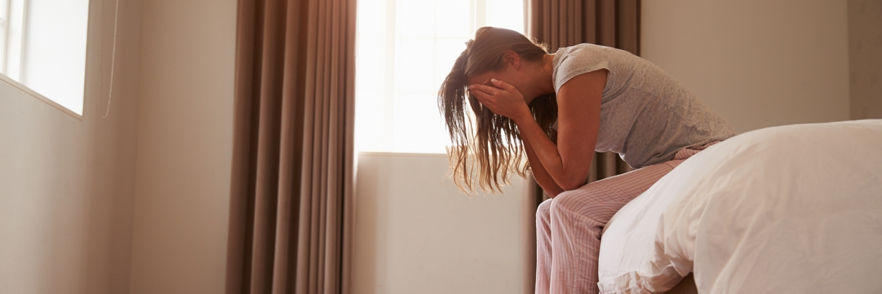 My Thoughts on the Bad Days of Fibromyalgia woman sits on the edge of her bed with her head in her hands