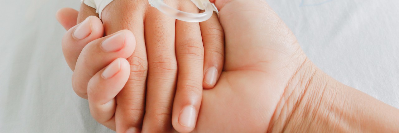mother holding child's hand who fever patients have IV tube.