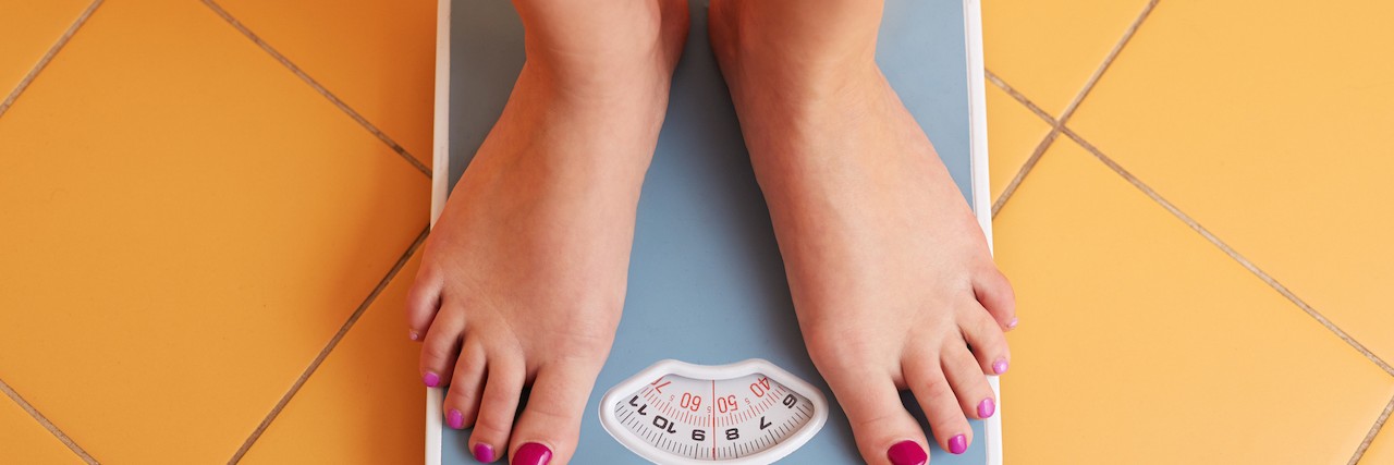A pair of female feet standing on a bathroom scale