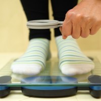 woman feet on weighing scales looking weight over magnifying