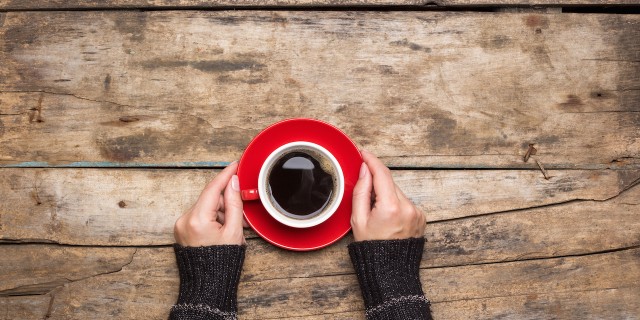 Female hands holding red cup of coffee