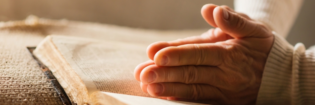 Using Prayer to Cope With Bipolar Depression woman's hands praying over a bible