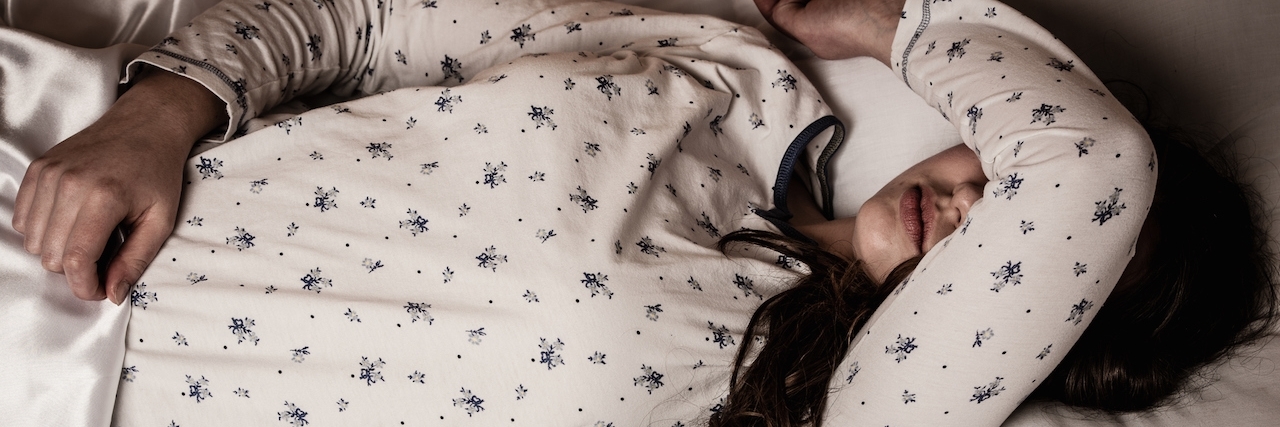 Woman lying in bed with one arm over her eyes