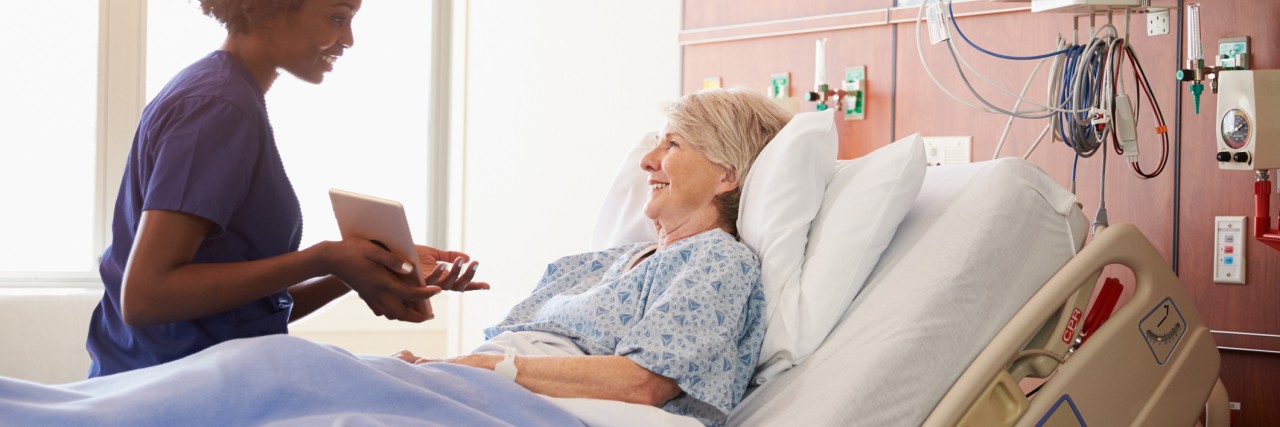 hospital nurse talks to patient in hospital bed