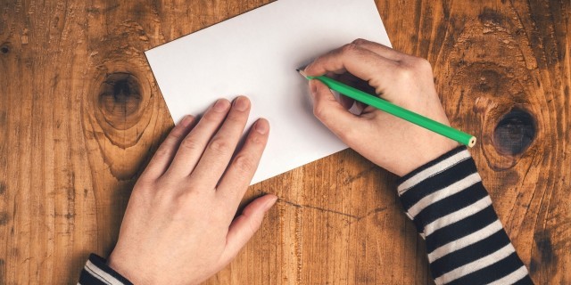 Woman writing recipient address on mailing envelope