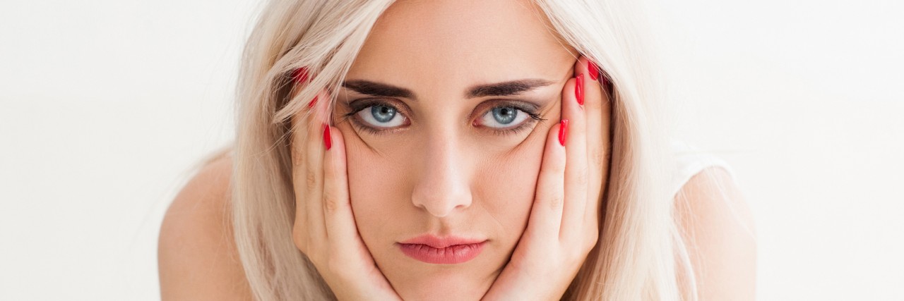 What Life With Obsessive Compulsive Disorder Is Like woman who looks annoyed, her hands on her cheeks