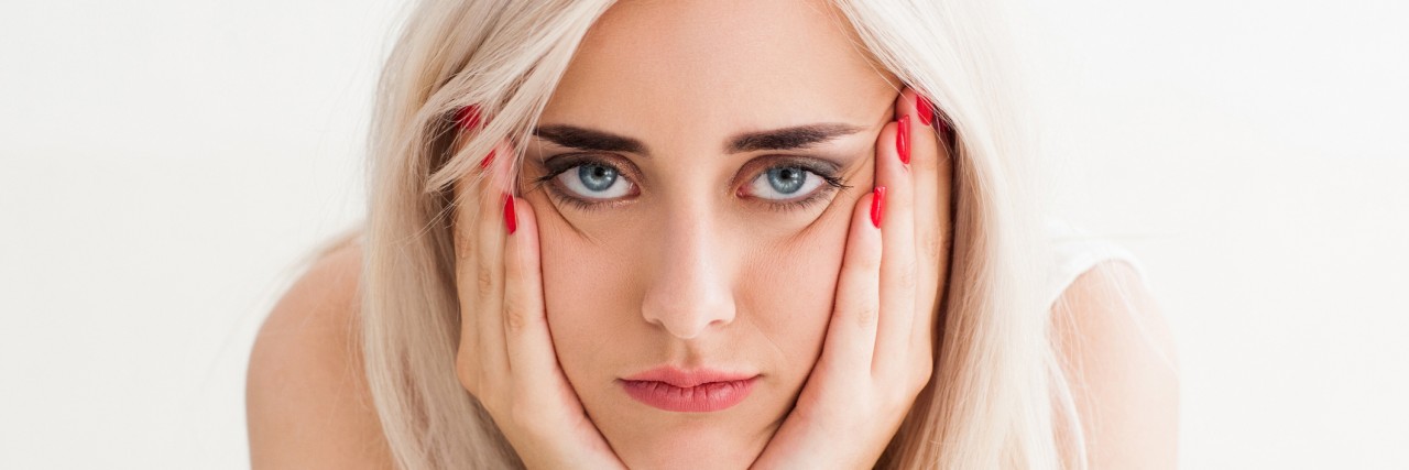 woman who looks annoyed, her hands on her cheeks