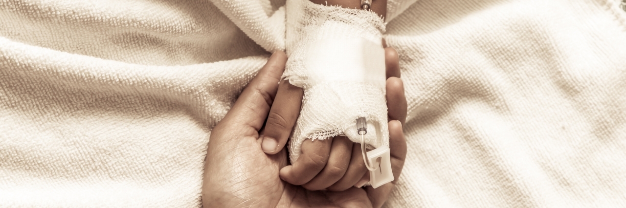 mother holding child's hand who have IV solution in the hospital in vintage color tone