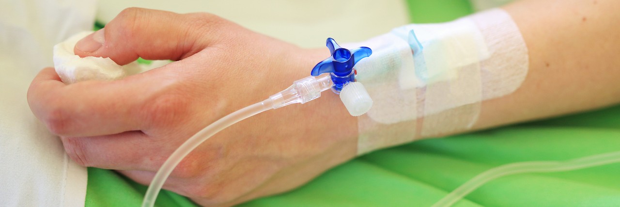 Why Money and Insurance Prevent Treatment for Rare and Chronic Disease Patient hand with infusion on hospital bed