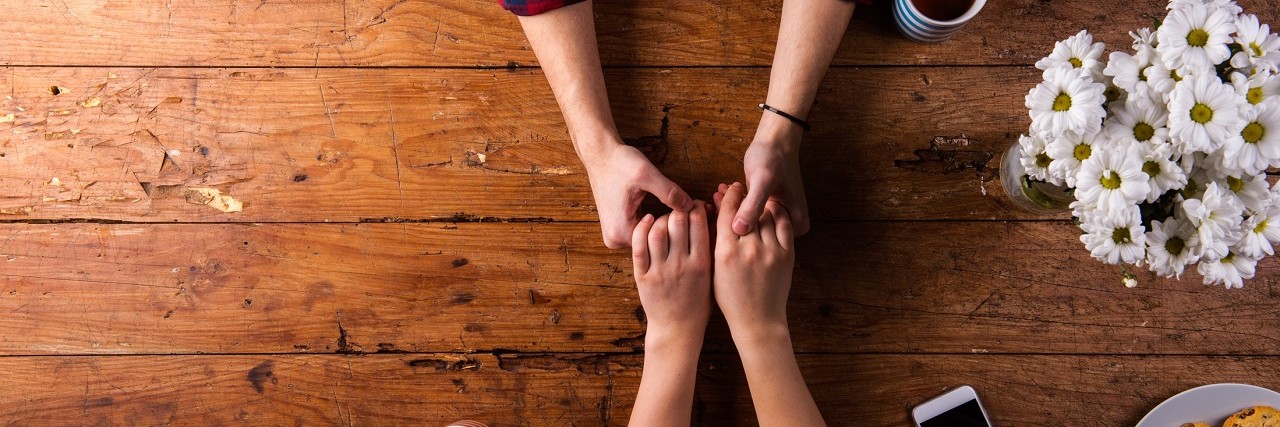Speaking Freely in a Relationship When You Have a Mental Illness A couple holds hands across a table.