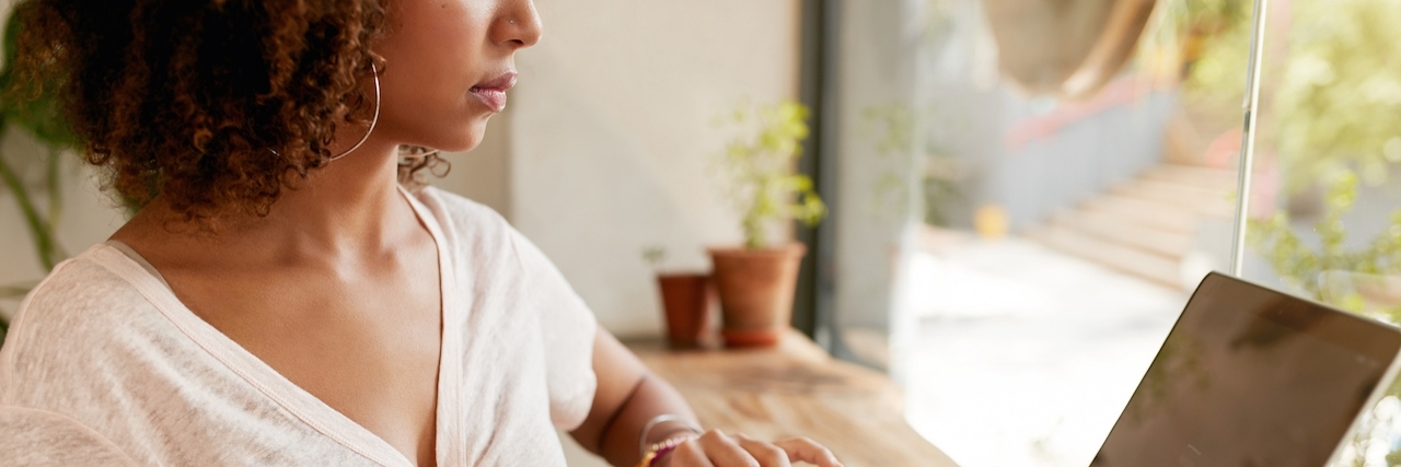 What to Know When First Feeling Fibromyalgia Symptoms Cropped image of young woman working on laptop while sitting in cafe. African girl using laptop computer with a cup of coffee on table.
