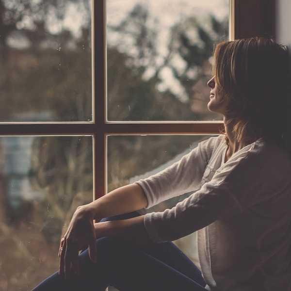 Woman sitting on a windowsill, looking outside