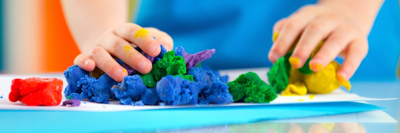 Child playing with colorful dough on table