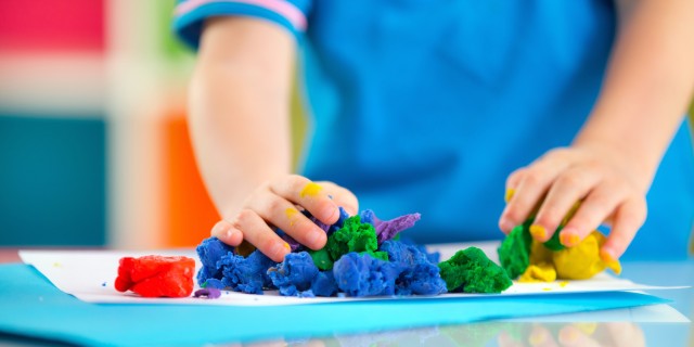 Child playing with colorful dough on table