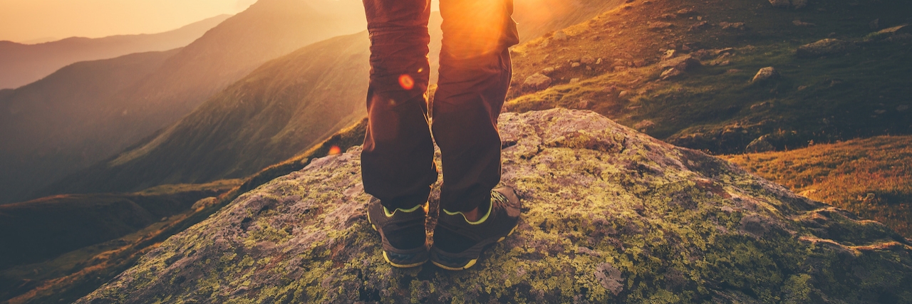 Why I Keep Moving Forward in My Battle With Mental Illness Young Man Traveler feet standing alone with sunset mountains